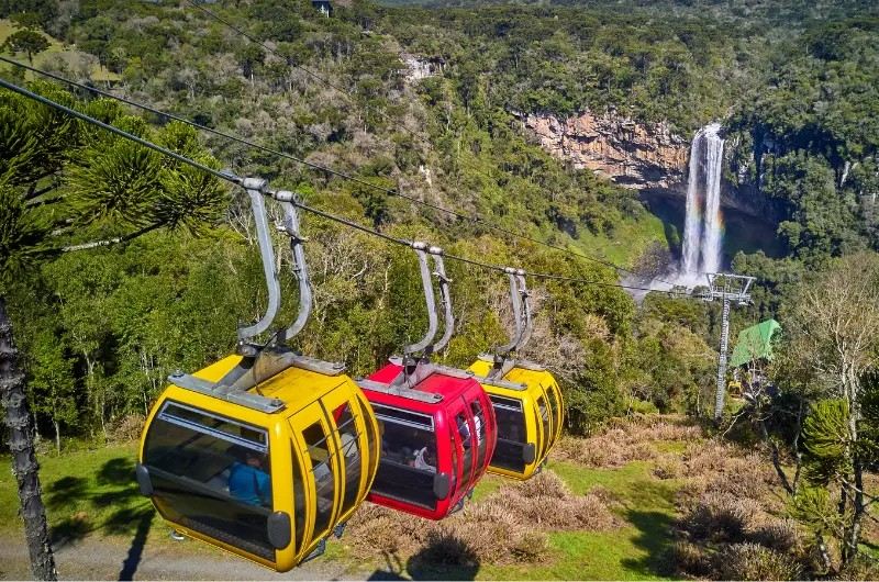 Bondinhos amarelos e vermelho com a cascata ao fundo
